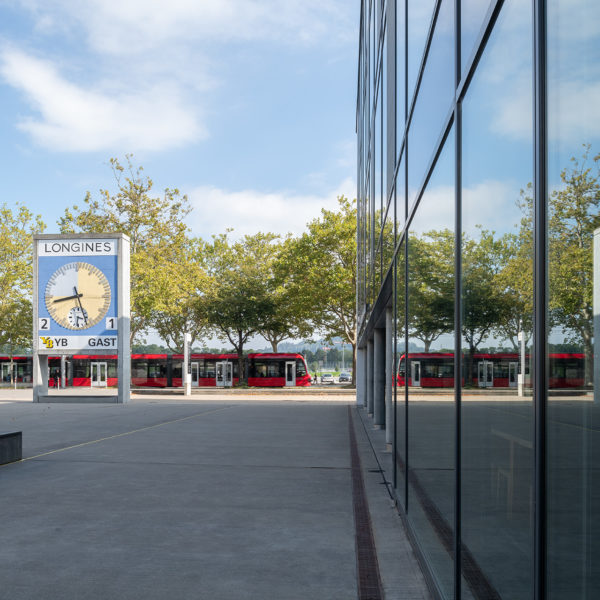 Linker Rand Schulgebäude bwd Bern mit der Tramstation und rotem Tram vor dran.