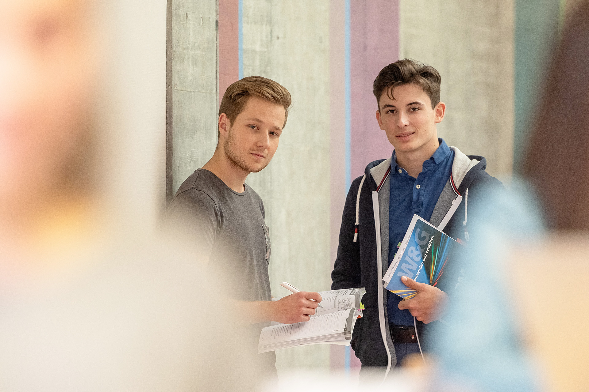 Zwei Lernende im Gang stehend mit Bücher in den Händen.