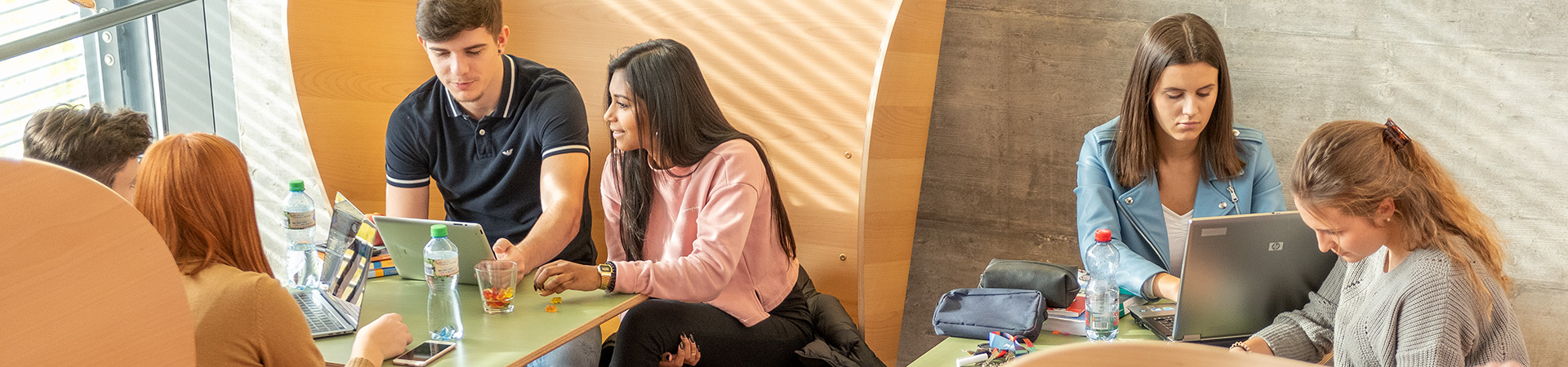 Lernende in der Pause auf verschiedene Ohrsessel aus Holz sitzend.