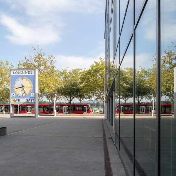 In der Mitte des Bildes ist die YB Uhr dahinter Bäume sowie das 9 Tram. Links ist die Gebäudefront vom bwd Gebäude.