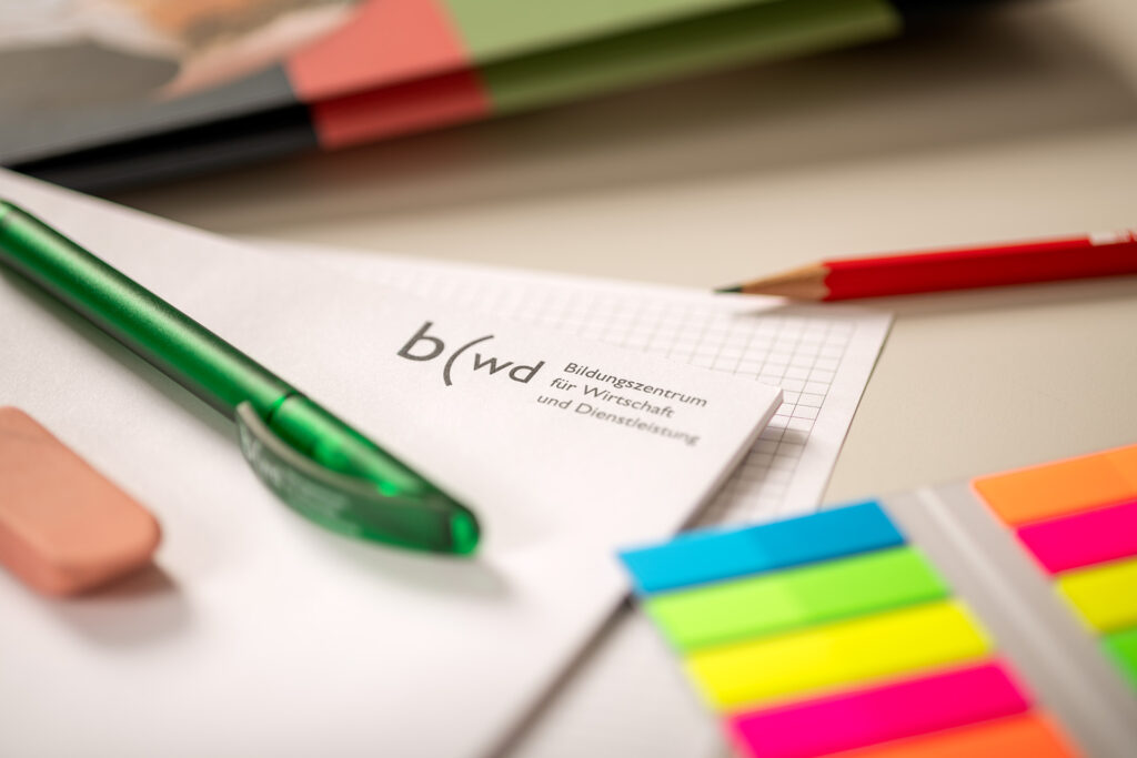 Nahaufnahme von Schreibblock, Kugelschreiber, Bleistift, Radiergummi und Merkkleber. Durcheinander auf dem Pult gelegt.